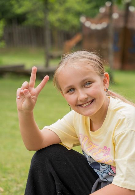 Smiling pupil showing a peace sign outdoors