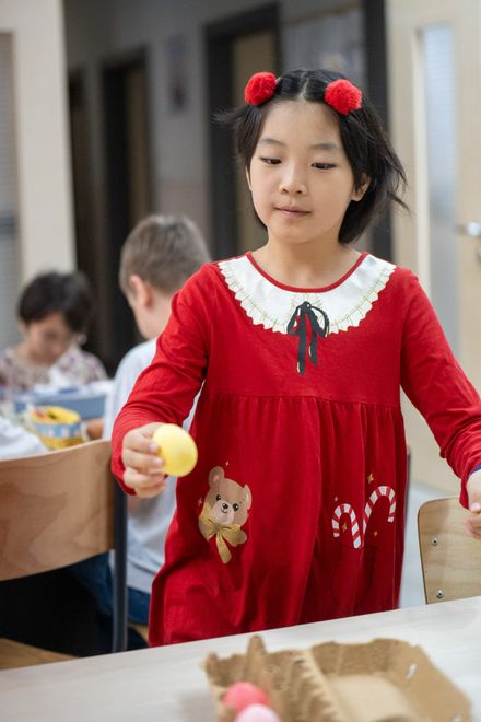 Pupil in a red dress holding an Easter egg